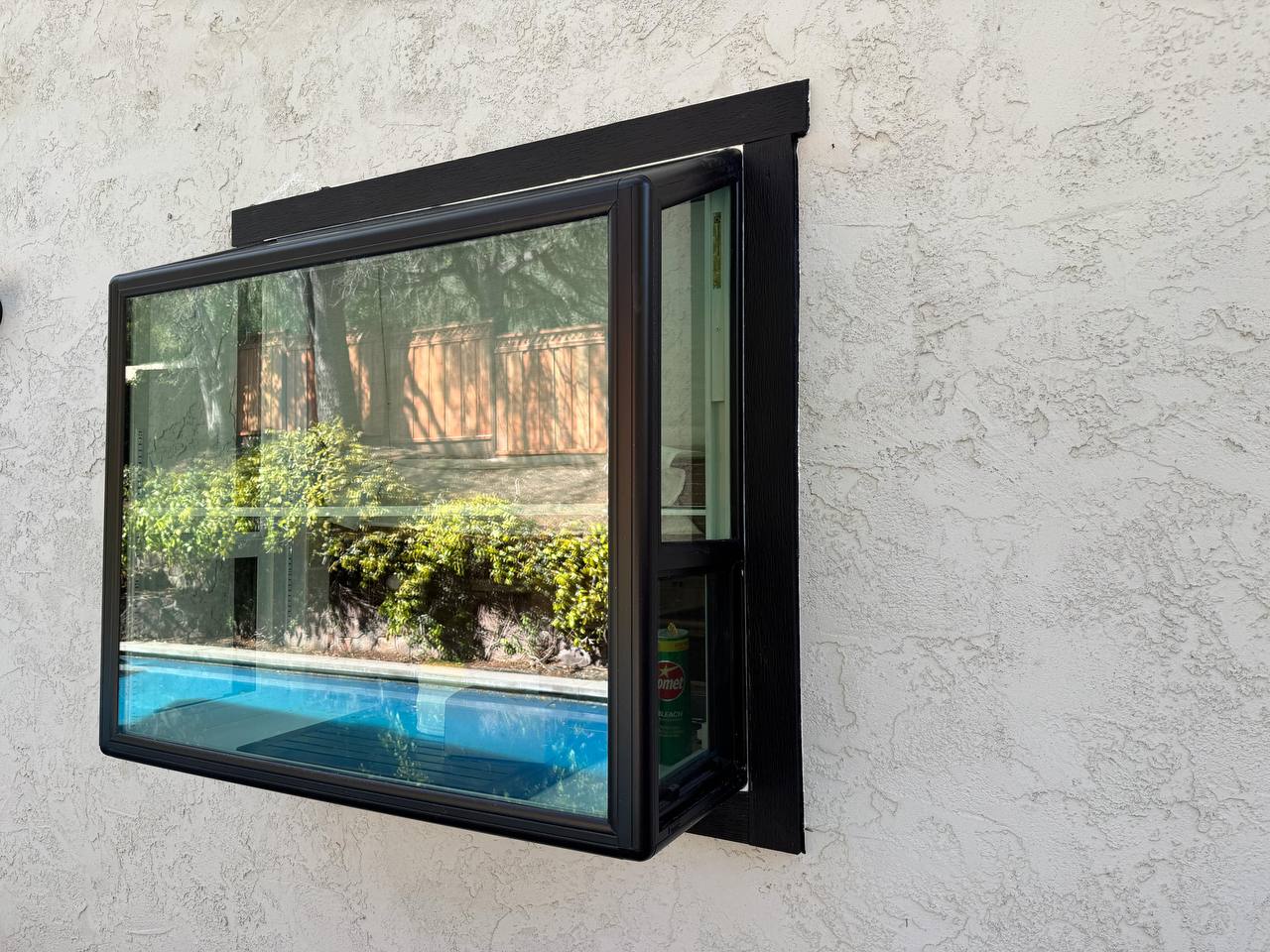 Black-frame casement window with garden reflection — Milari installation